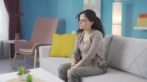 Woman Sitting Thoughtfully on Couch in Living Room