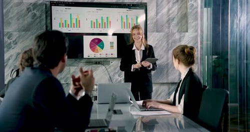 Team members listening attentively to female colleague presenting analytics report in office meeting