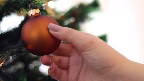 Hand Decorating Christmas Tree with Bronze Ornament