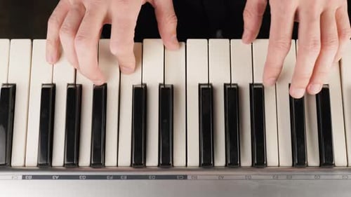Two hands play gentle modern piano music on a piano. Concept of stay at home and make some music