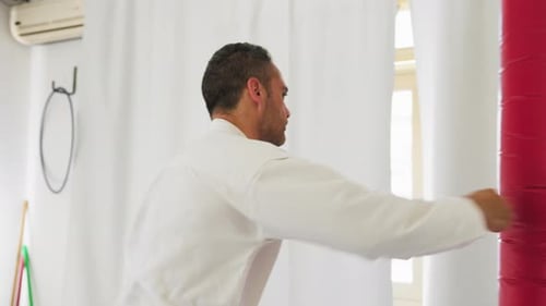 Man Punching a Red Martial Arts Bag Indoors