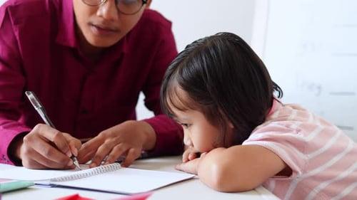 Geduldiger asiatischer Tutor erklärt konzentrierten kleinen Mädchen während des Privatunterrichts Grammatik