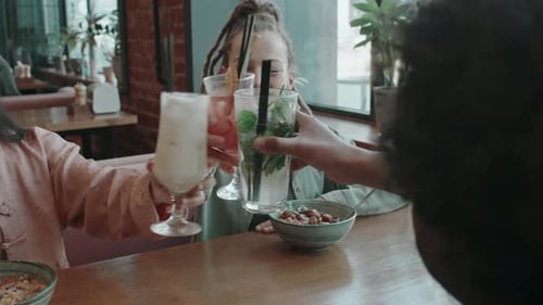 Groupe de trois amis au café souriant, tout en levant et en faisant tinter leurs verres