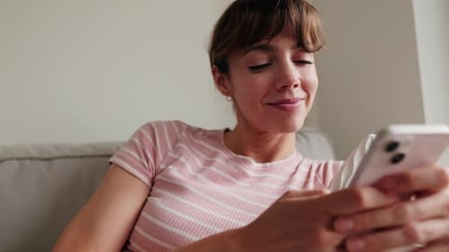 Smiling Woman Using Mobile Phone on Couch