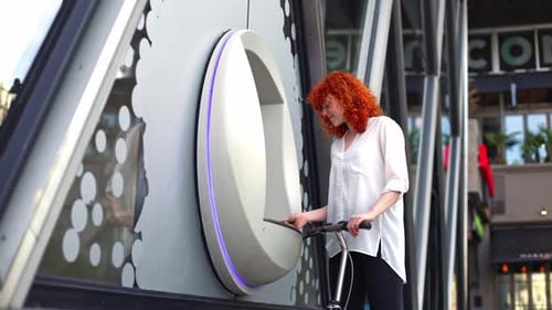 Young Woman Using a Smartphone to Rent an Electric Scooter in the City