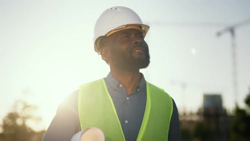 Portrait of Foreman Examining Construction Area Black Man with Roll of Drawings Professional Builder