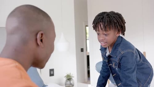 Happy african american father and son embracing at home, slow motion