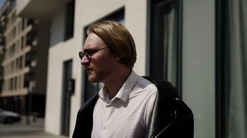 A Brutal Man Walks Along the Building and Puts on a Black Jacket