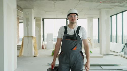 Construction Worker Carrying Toolbox in High-Rise Apartment