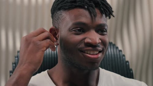 Man Inserts Wireless Earbud Into Ear While Smiling