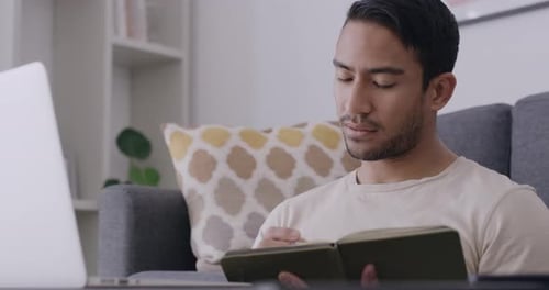 Young Adult Studying with Laptop and Notebook at Home