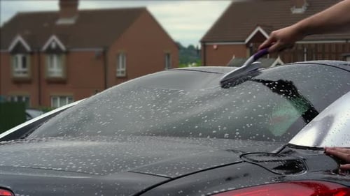 Car Wash Detailer Cleaning Vehicle in Suburban Neighborhood