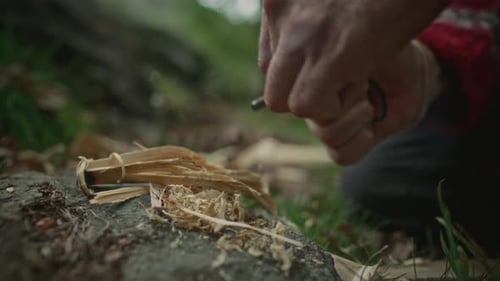 Man starting fire with flint in wilderness setting