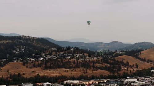 Hot Air Balloon Over City and Mountains