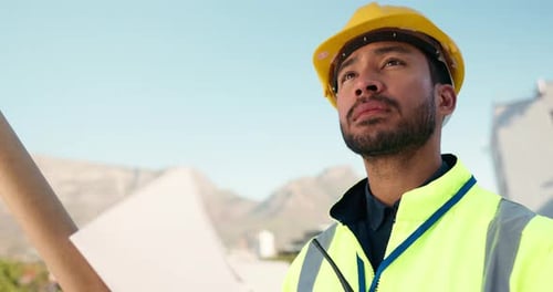 Construction Worker Inspects Blueprints at Site