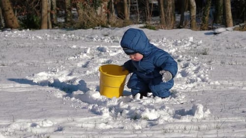 Child Playing in Snow with Yellow Bucket