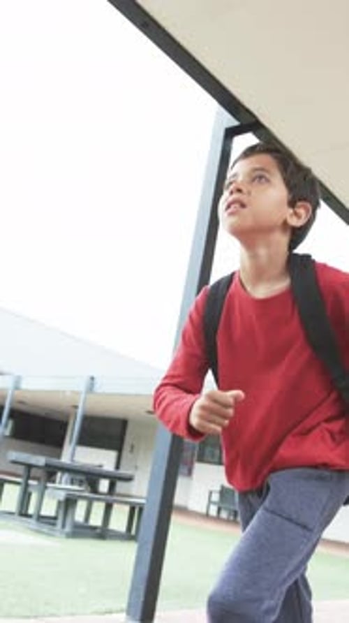 Vertical video: In a school setting, a young biracial student is captured mid-stride
