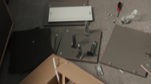 Pièces et outils de tiroir Flatpack éparpillés sur le sol lors de l'assemblage à la maison