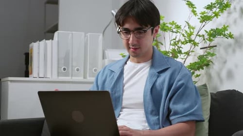 Young caucasian man working remote in home office, using laptop computer during video call meeting.