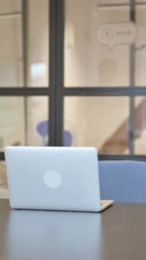 Man Sits Down at Desk and Opens Laptop
