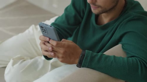 Männliche Freelancer-Nachrichten auf dem Smartphone in Innenräumen