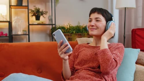 Woman Listens to Music with Headphones at Home