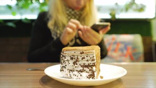 Close-up of blond hair young woman with mobile phone surfing on internet at cafe