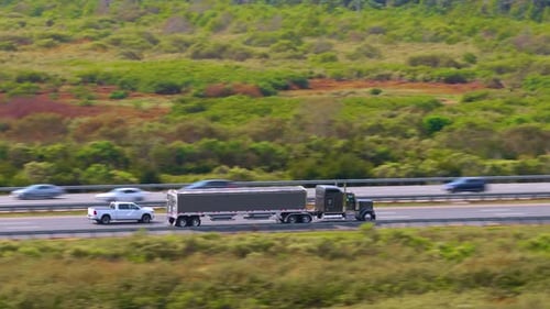 Lorry Semi Truck Delivering Cargo in Hauling Trailer on Multilane American Freeway