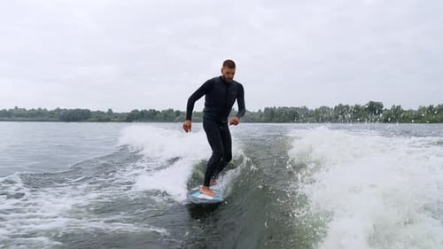 Man Wakesurfing on Lake in Black Wetsuit