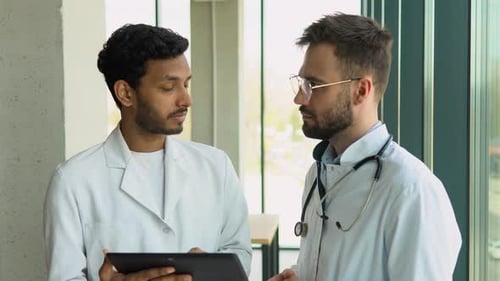 Doctors Discussing on Tablet in Hospital Setting