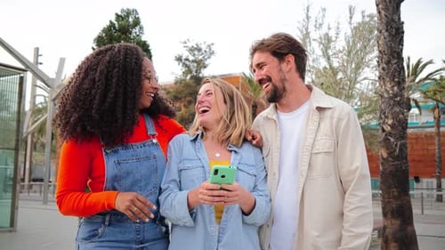 Three Friends Laughing While Looking at Phone