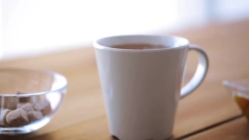 Hand adds sugar cubes to hot cup of tea or coffee unhealthy eating concept