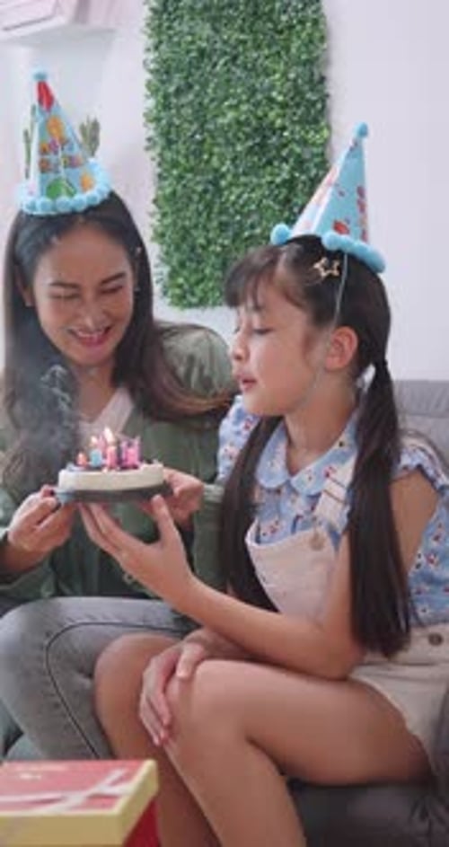 Girl Blowing Out Birthday Candles with Woman