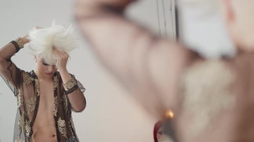 Person Applies White Wig in Front of Mirror