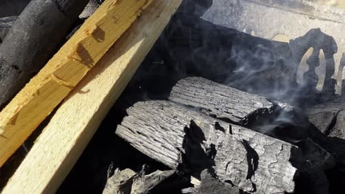 Smoking Charcoal and Wood Pieces in a Container