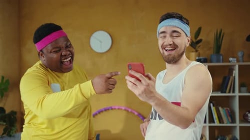 Laughing Men Watching Smartphone Content at Home