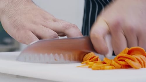 Professional Chef Slicing Fresh Carrots on Cutting Board