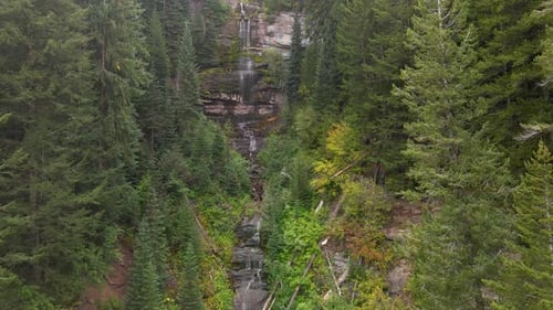 Luftaufnahme des Wassers eines Wasserfalls, der mitten im grünen Wald von den Felsen herunterfällt.