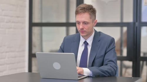 Man in Suit Gives Thumbs Up at Desk