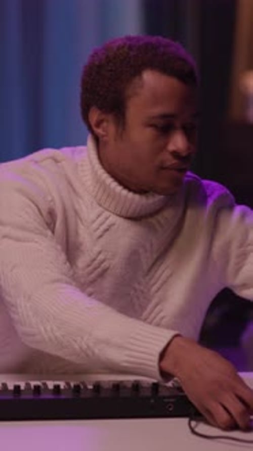 Man Making Music with Midi Keyboard at Night
