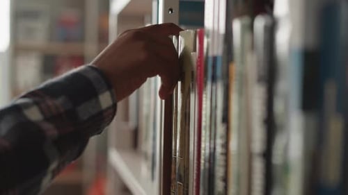 Man Hand Picks Up Book From Shelf in Library