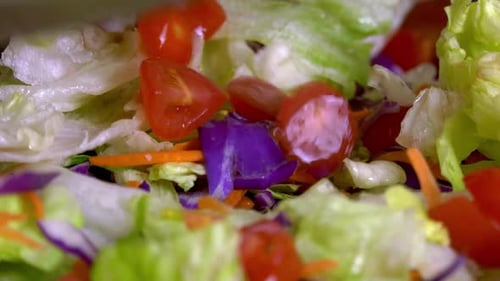 Slices of cherry tomatoes dropped into a fresh salad. Close up shot