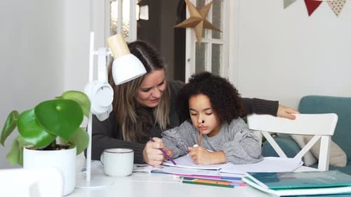 Woman Helping Little Girl with Homework at Table