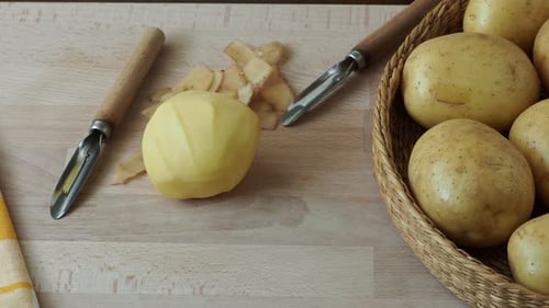 Peeled Potato and Peelers on Wooden Board