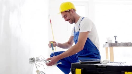 Electrician Repairing Outlet Inside Home Under Construction