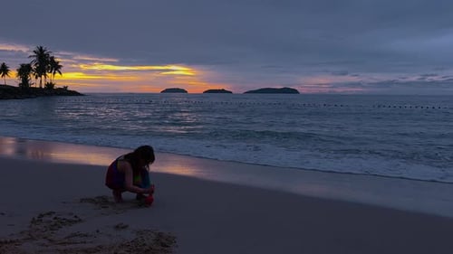 Little Girl Playing on Wet Sand Tropical Beach at Sunset at Kota Kinabalu in Silhouette