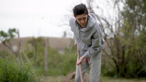 Teenage Boy Farmer Working in Garden Using Gardening Tools Adolescent Farmer Tending to Crops with