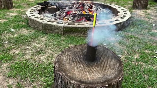 Firework Rocket Takes Off During Daytime In Front Of Fire Pit.
