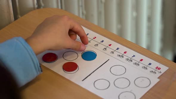 Child using math counting sheet with colorful counters, People Stock ...