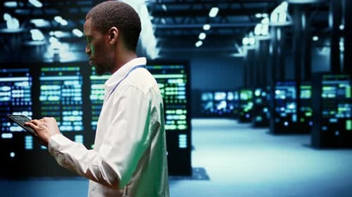 Afroamerikanischer IT-Administrator überprüft Servercluster im Rechenzentrum